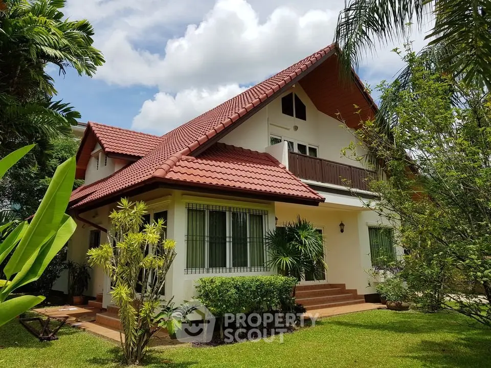 Charming two-story house with red-tiled roof and lush garden, perfect for family living.