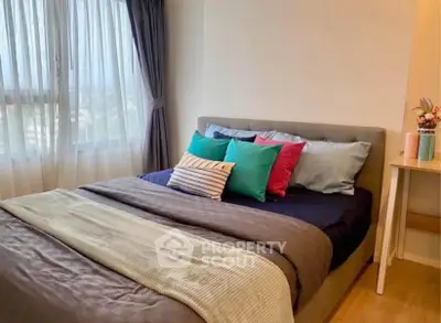 Cozy bedroom with stylish decor and natural light from large window.