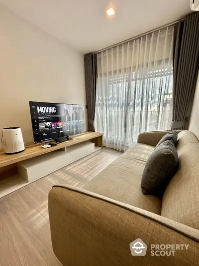 Modern living room with cozy sofa and large TV, featuring floor-to-ceiling windows and elegant curtains.