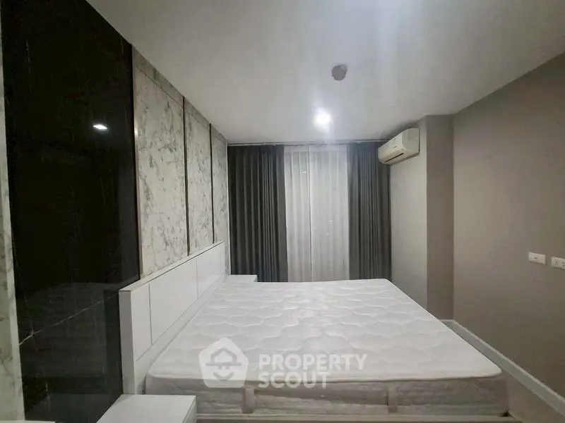 Modern bedroom with marble accent wall and air conditioning in a stylish apartment.