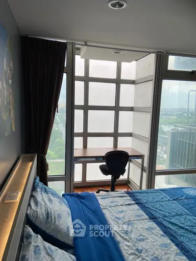 Modern bedroom with floor-to-ceiling windows and a study nook offering a stunning city view.