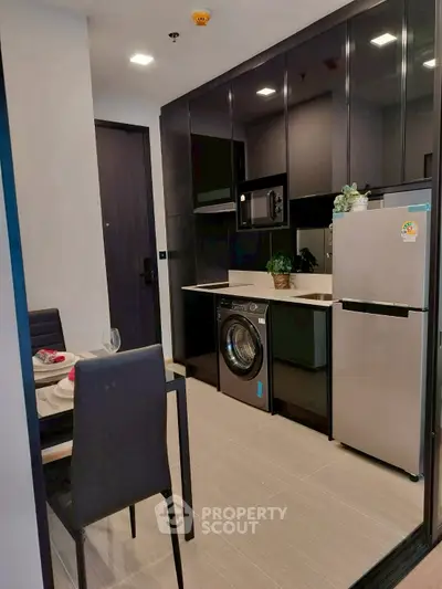 Modern compact kitchen with sleek black cabinets and integrated appliances.