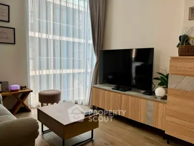 Modern living room with large TV, stylish furniture, and floor-to-ceiling window for natural light.