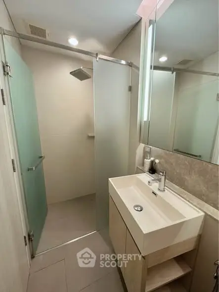 Modern bathroom with glass shower and sleek vanity in stylish apartment.