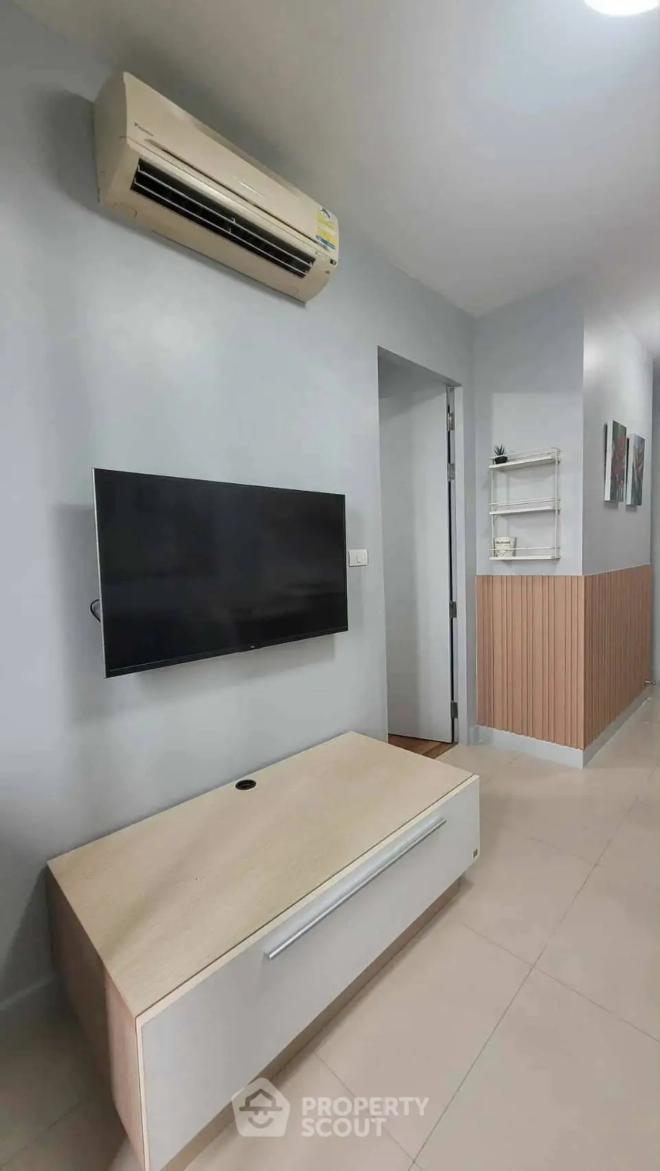 Modern living room with wall-mounted TV and air conditioning unit, featuring sleek furniture and minimalist decor.