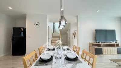 Modern dining area with elegant table setting and open view to living room and staircase.