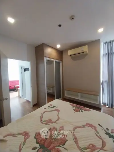 Cozy bedroom with floral bedding and mirrored wardrobe in modern apartment.