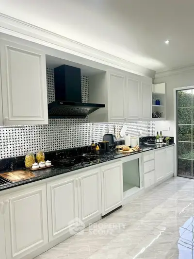 Elegant kitchen with white cabinetry and modern appliances, featuring a sleek black backsplash and marble flooring.