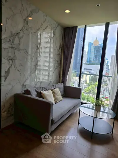 Modern living room with city view, featuring marble accent wall and cozy gray sofa.
