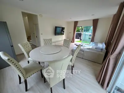 Spacious living room with elegant dining set and modern decor, featuring large windows for natural light.