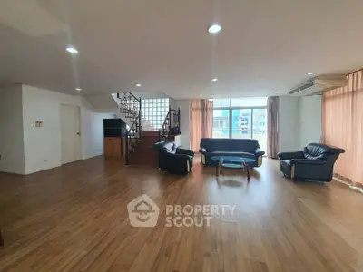 Spacious living room with wooden flooring and modern furniture in a bright apartment.