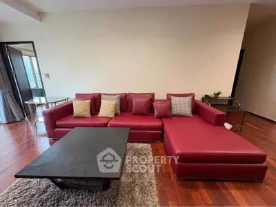 Spacious living room with elegant red sectional sofa and modern coffee table on hardwood floor.