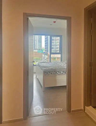 Modern bedroom with city view, featuring large windows and stylish decor in a high-rise apartment.