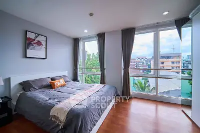Spacious bedroom with large windows offering a stunning city view, featuring modern decor and cozy ambiance.