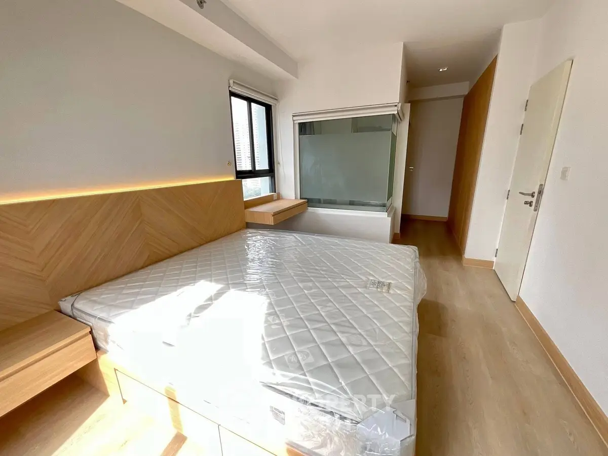 Modern bedroom with wooden flooring and large window for natural light