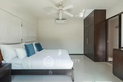Spacious bedroom with modern furnishings and ample natural light, featuring a ceiling fan and built-in wardrobe.