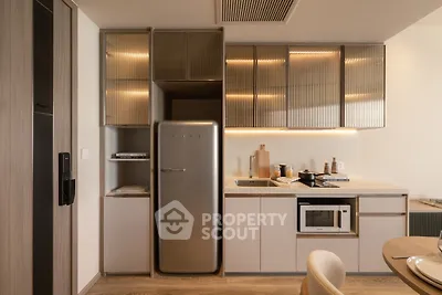 Modern kitchen with sleek cabinets, integrated fridge, and microwave in stylish apartment.