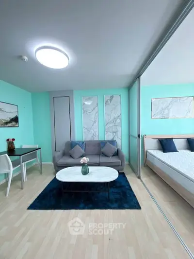 Modern living room with stylish decor and adjacent bedroom in open layout apartment.