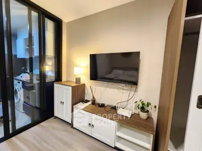 Modern living room with sleek TV setup and adjacent laundry area in stylish apartment.