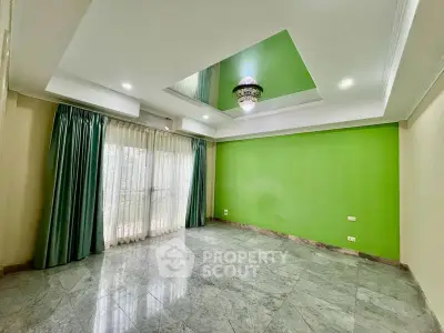 Spacious living room with green accent wall and elegant chandelier