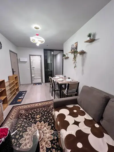 Cozy living room with modern decor and dining area, featuring stylish lighting and wall shelves.