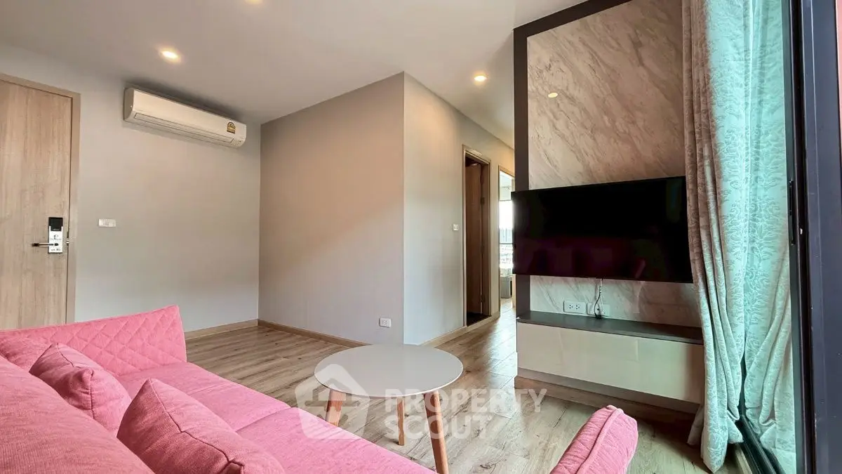 Modern living room with pink sofa and wall-mounted TV in stylish apartment.