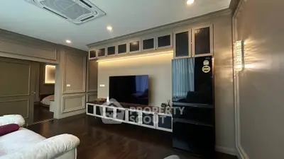 Luxurious living room with modern entertainment center and sleek black fridge, perfect for stylish living.