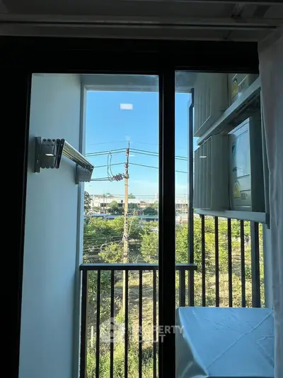 Charming apartment balcony with scenic view of lush greenery and clear blue sky, perfect for relaxation.