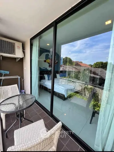Charming balcony with glass doors overlooking a serene garden view, perfect for relaxation.