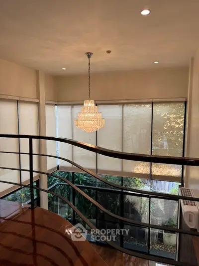 Elegant interior with chandelier and large windows overlooking lush greenery