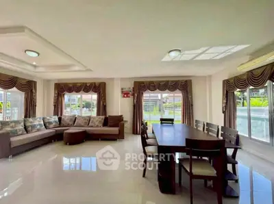 Spacious living room with elegant dining area and large windows offering natural light.