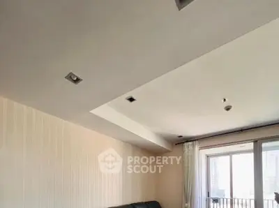 Modern living room with large window and sleek ceiling design.