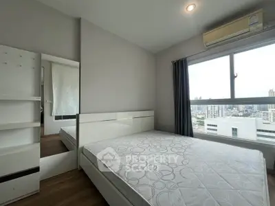Modern bedroom with city view, featuring a large window and air conditioning unit.
