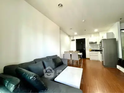Modern open-layout living room and kitchen with sleek furniture and appliances.