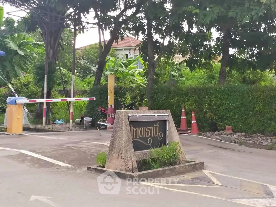 Charming entrance with lush greenery and secure access gate in a serene neighborhood.