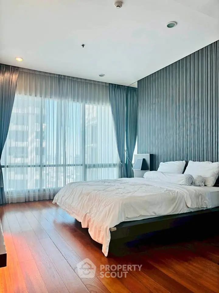 Luxurious bedroom with floor-to-ceiling windows and elegant decor in modern apartment.
