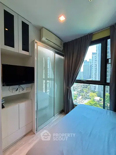Modern bedroom with city view, featuring sleek built-in storage and a wall-mounted TV.