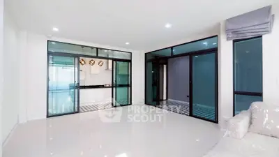 Spacious modern living room with glass doors leading to a sleek kitchen