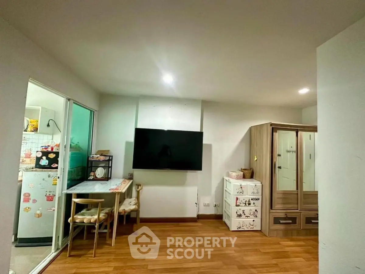 Cozy living room with modern decor and wooden flooring, featuring a wall-mounted TV and stylish furniture.