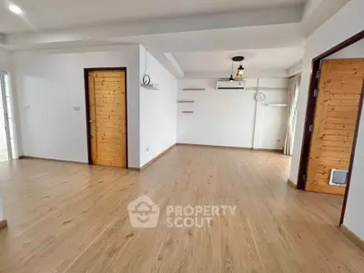 Spacious open-plan living room with wooden flooring and modern lighting.