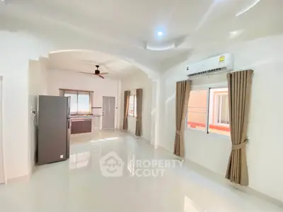 Spacious open-plan living area with modern kitchen and large windows.