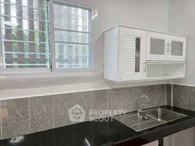 Modern kitchen with sleek black countertop and stainless steel sink, featuring a window with natural light.