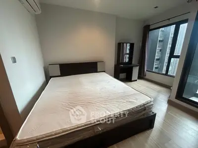 Spacious bedroom with large window and modern furniture in urban apartment