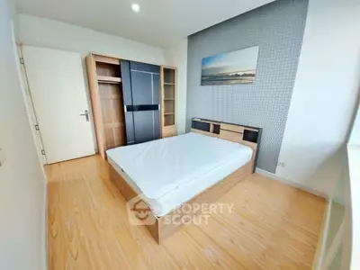 Modern bedroom with wooden flooring, stylish wardrobe, and contemporary wall art.