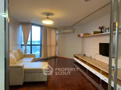 Spacious living room with modern decor and large window offering natural light and city views.
