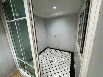 Modern small room with stylish black and white tiled floor and sliding glass doors.