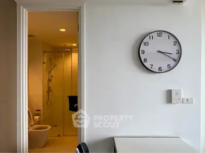Modern bathroom with glass shower and wall clock in a stylish apartment