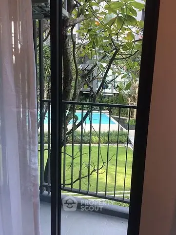 Charming balcony view overlooking lush garden and inviting pool area, perfect for relaxation.