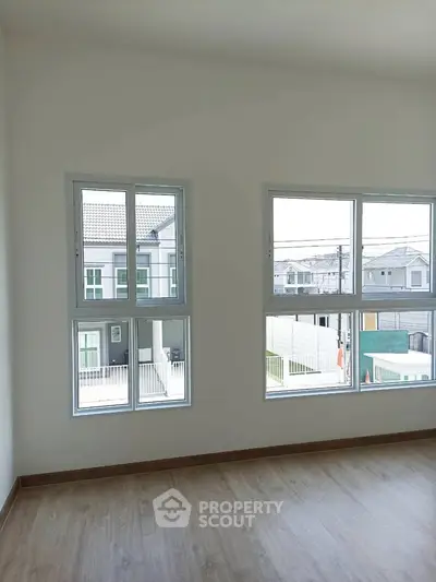 Bright and airy room with large windows and wooden flooring in modern home.