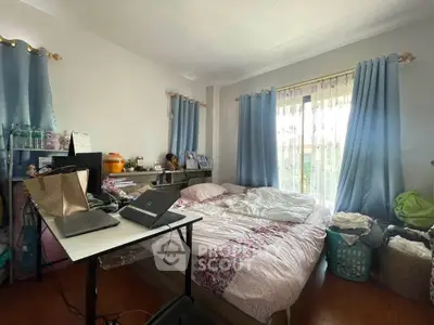 Cozy bedroom with natural light, featuring a work desk and stylish curtains.